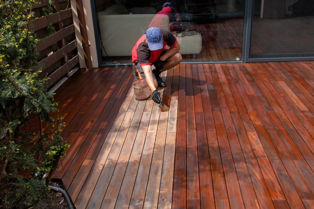 Wood,Worker,Applying,Nourishing,Deck,Oil,With,Paintbrush,On,Cleaned