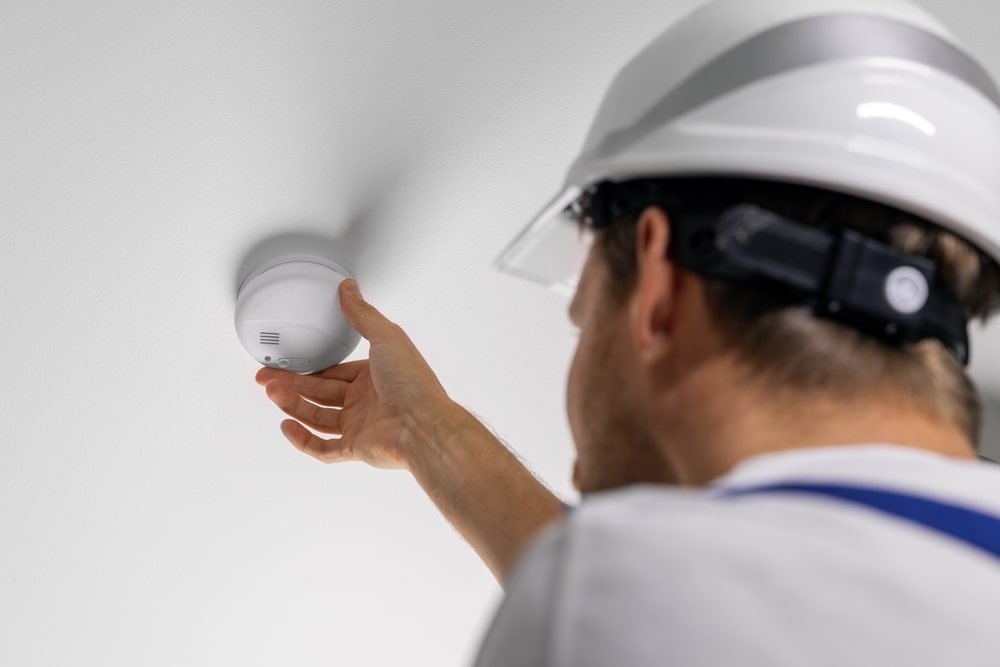 Worker,Installing,Photoelectric,Smoke,Detector,On,House,Ceiling.,Home,Security