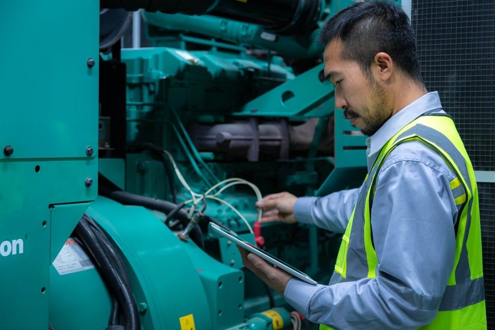Ingenieur gebruikt een tablet voor controle en onderhoud van een dieselinstallatie